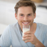 A man smiling while holding a glass of milk.